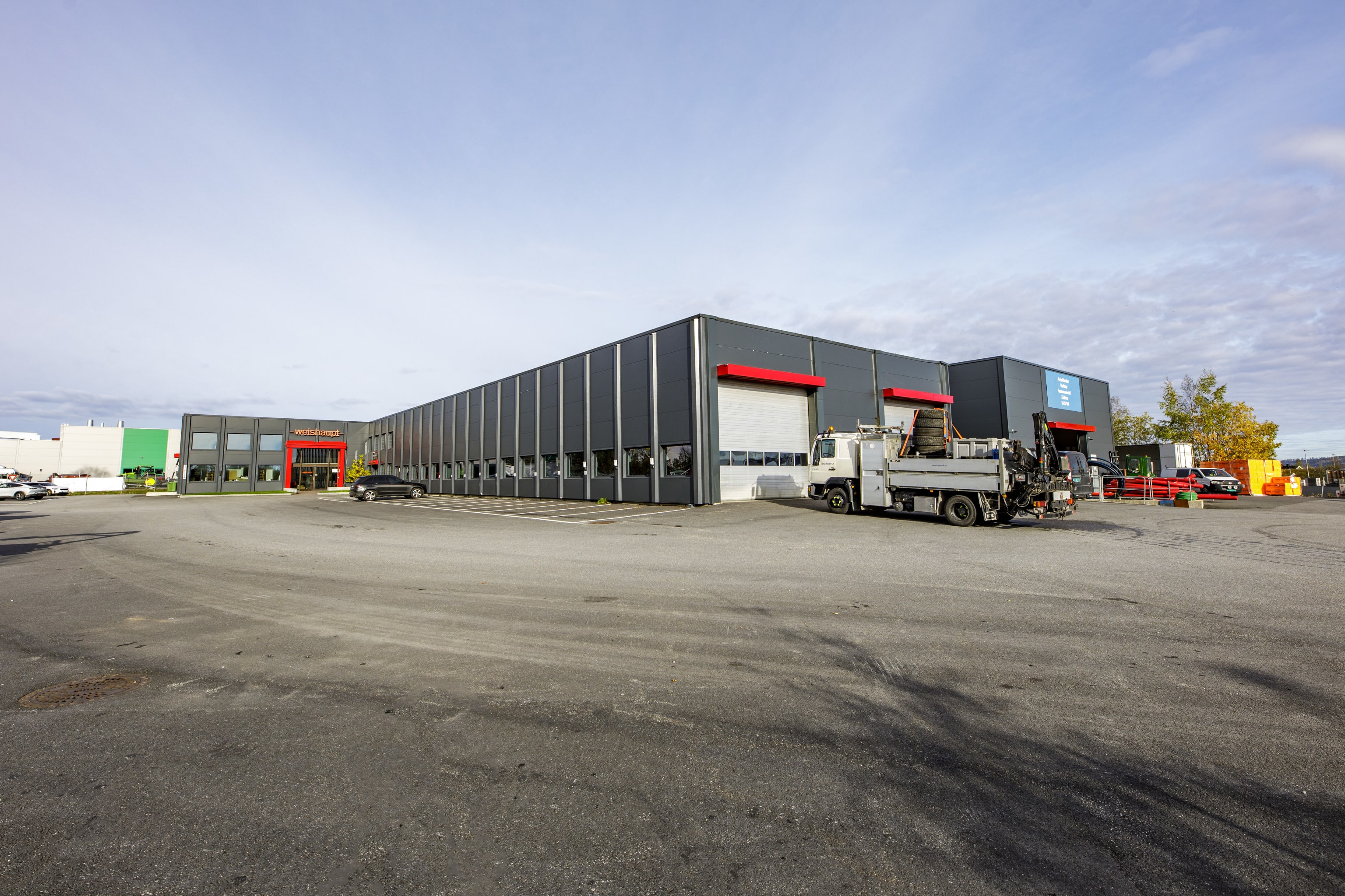 Fasade av næringsbygg bakside med parkering utenfor